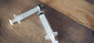 white and black plastic syringe on brown wooden table