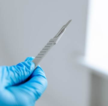 a person in blue gloves holding a toothbrush