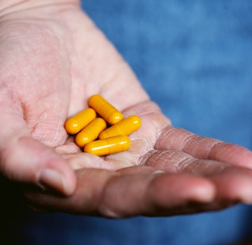 yellow medication pill on persons hand